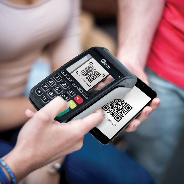 Close up shot on a customer's hand while holding mobile smart phone over credit card reader for contactless payment transaction.